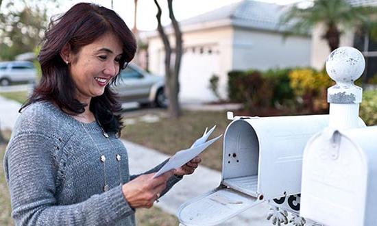 Woman reading letters that she got from her mailbox.