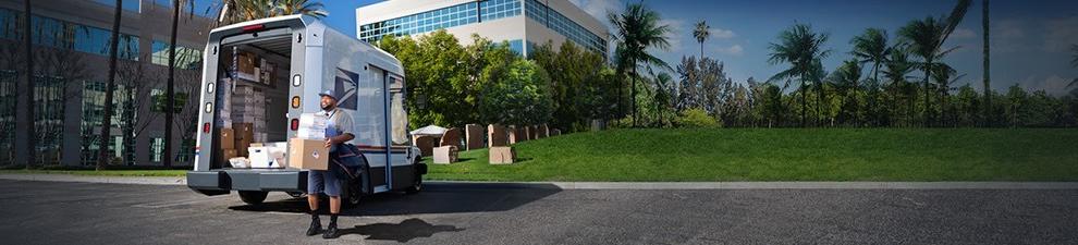 Letter carrier ready to deliver packages unloaded from the back of a USPS Next-Generation Delivery Vehicle.